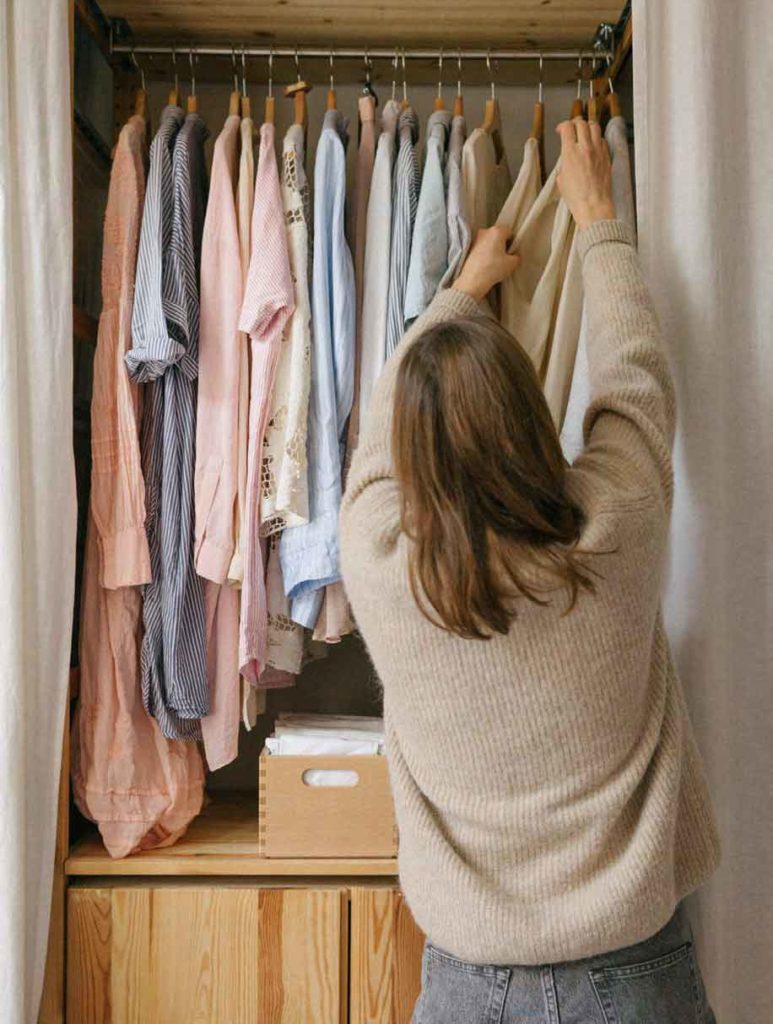Frau hängt Kleidung in den Schrank
